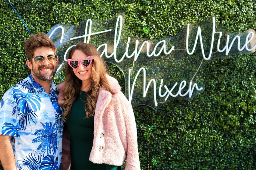 Couple posing in front of a Catalina Wine Mixer hedge sign at Catalina Island Company