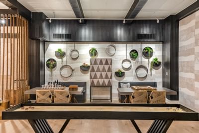 24-Hour Lounge with Games featuring a shuffleboard table, seating, and a lush wall decor at The Riverwalk Plaza Hotel