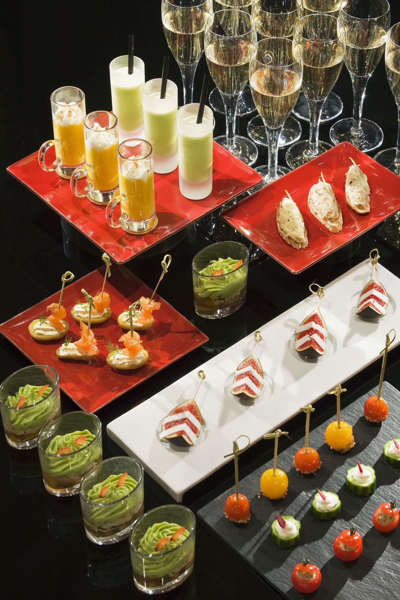 Assortment of appetizers and drinks arranged on a black surface in Restaurant Le W
