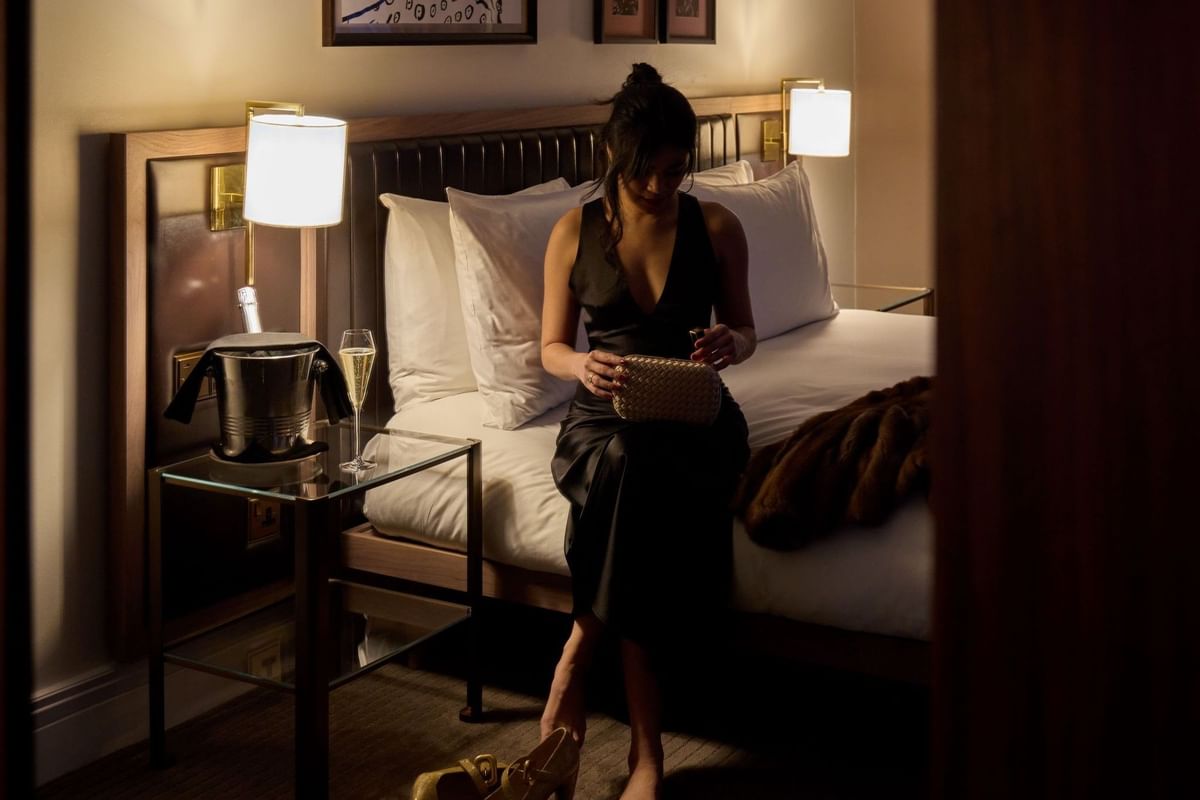 Woman in evening dress with champagne in a hotel room at The May Fair Hotel