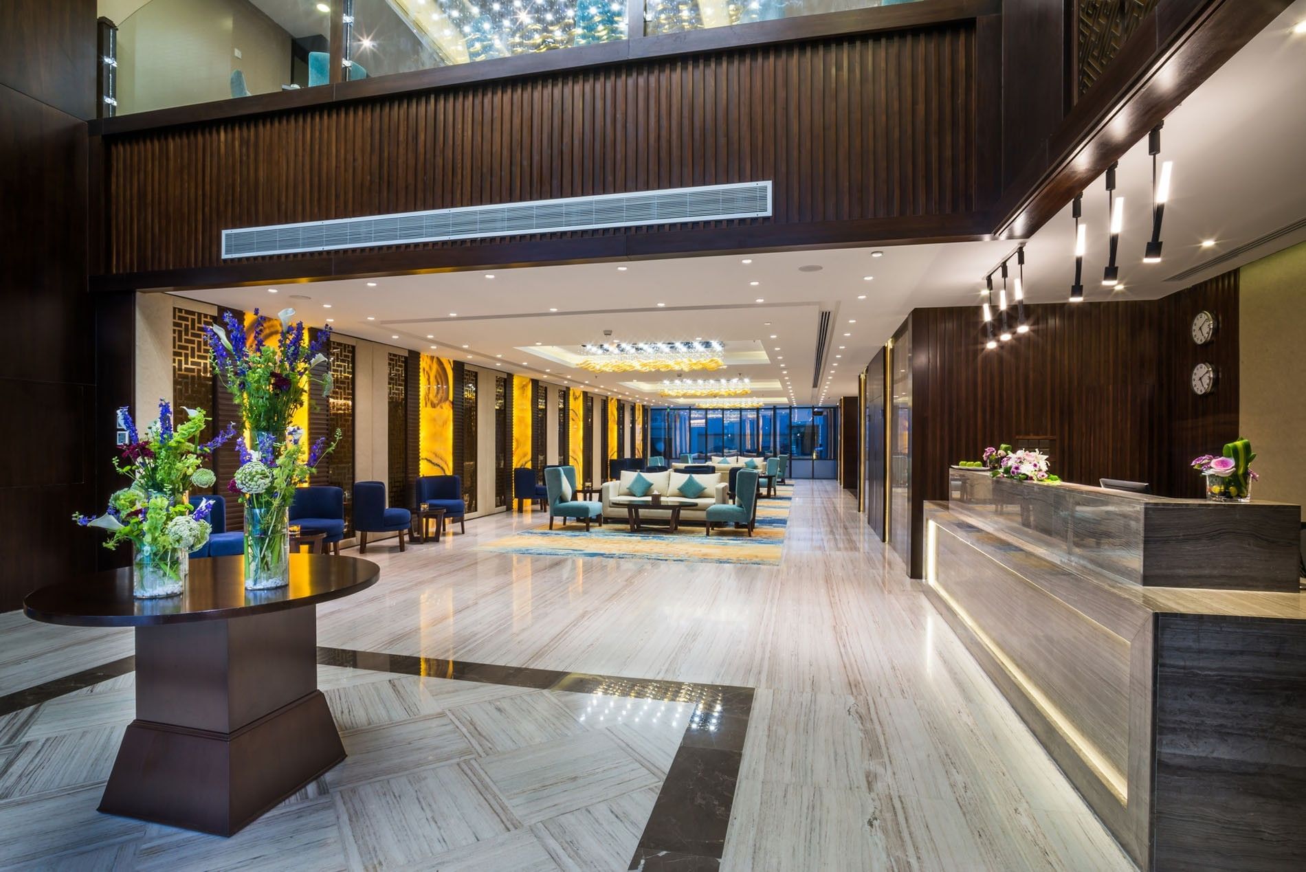 Vibrant flowers by a round table under a high ceiling in the lobby at Naviti By Warwick Dammam