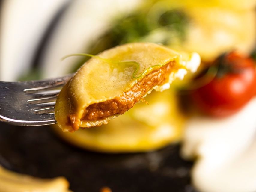 A piece of dumpling on a fork with sauce at EMME Restaurant