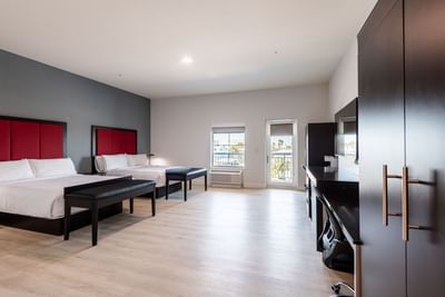 TV and side cupboard facing the beds in Two Bedroom Suite with wooden floors at The J Hotel, one of the top Dunedin hotels