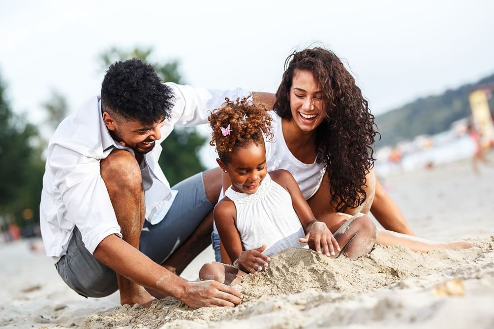 Familia haciendo castillos de arena en la playa de la Colección Curamoria