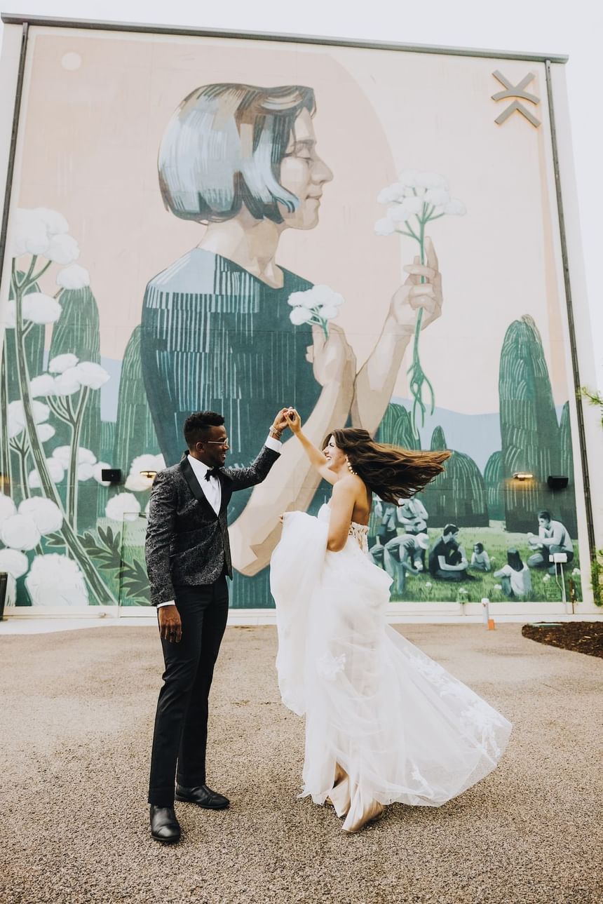 Wedding couple dancing in front of mural wall at Kinship Landing