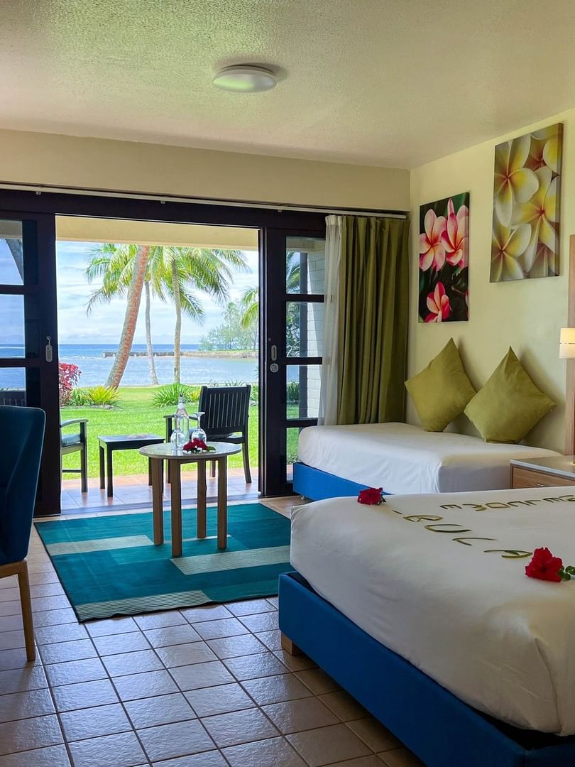 Two beds and balcony with ocean view in a room at The Naviti Resort in Korolevu.