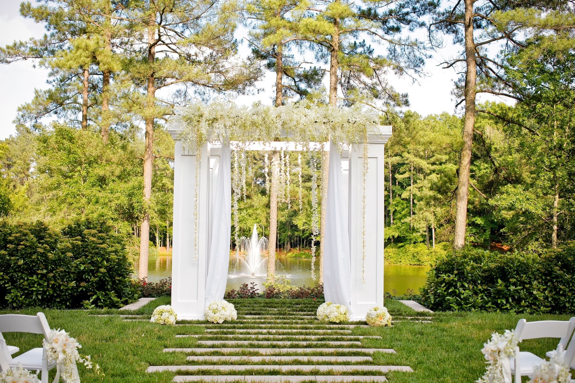 Outdoor wedding arch featuring white flowers in the Wedding Lawn at Umstead Hotel and Spa