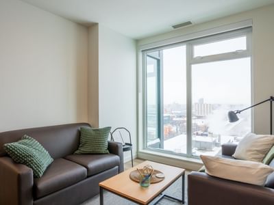 Two couches sit in a modern and well decorated sitting area with views to snowy cityscape below.
