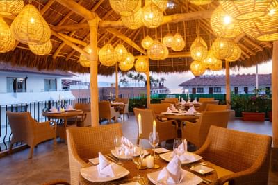 Outdoor terrace restaurant filled with wicker tables and chairs under glowing basket lamps at Casa Dona Susana