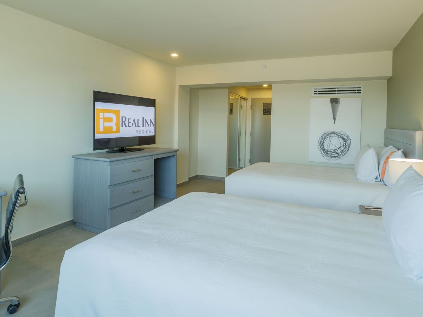 2 Double Deluxe room including a flat-screen TV, a desk area, and white textured bedding at Real Inn Mexicali