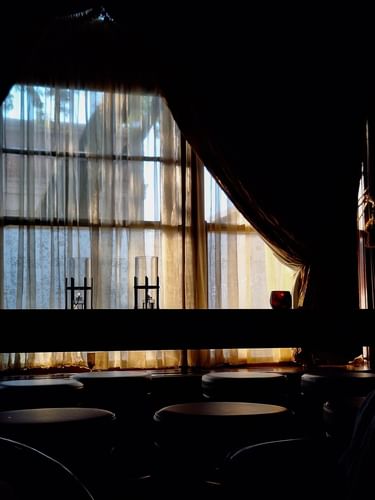 Glowing candles on a dark ledge by sheer curtains under a draped fabric in The Library at Warwick Melrose Dallas