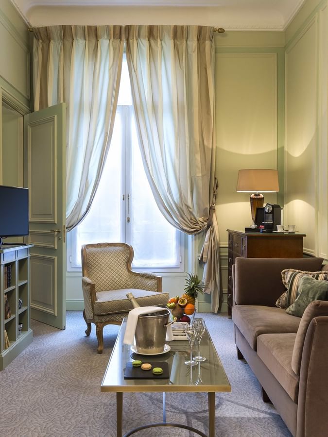 TV lounge with plush sofa by the window in Deluxe Parisienne Suite at Hotel Westminster Paris