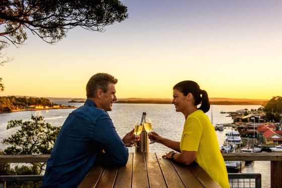 Couple having champagne with a harbor view at Strahan Village