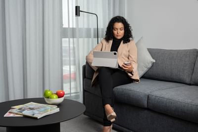 Lady using her tablet sitting on a couch at Nesuto Docklands