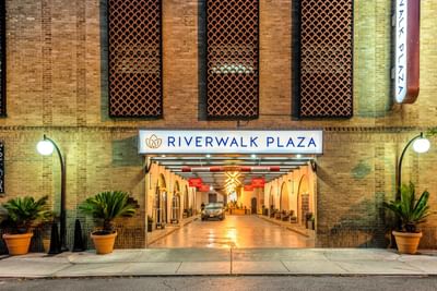 Garage entrance from the street with a decorative brick wall and potted plants at The Riverwalk Plaza Hotel