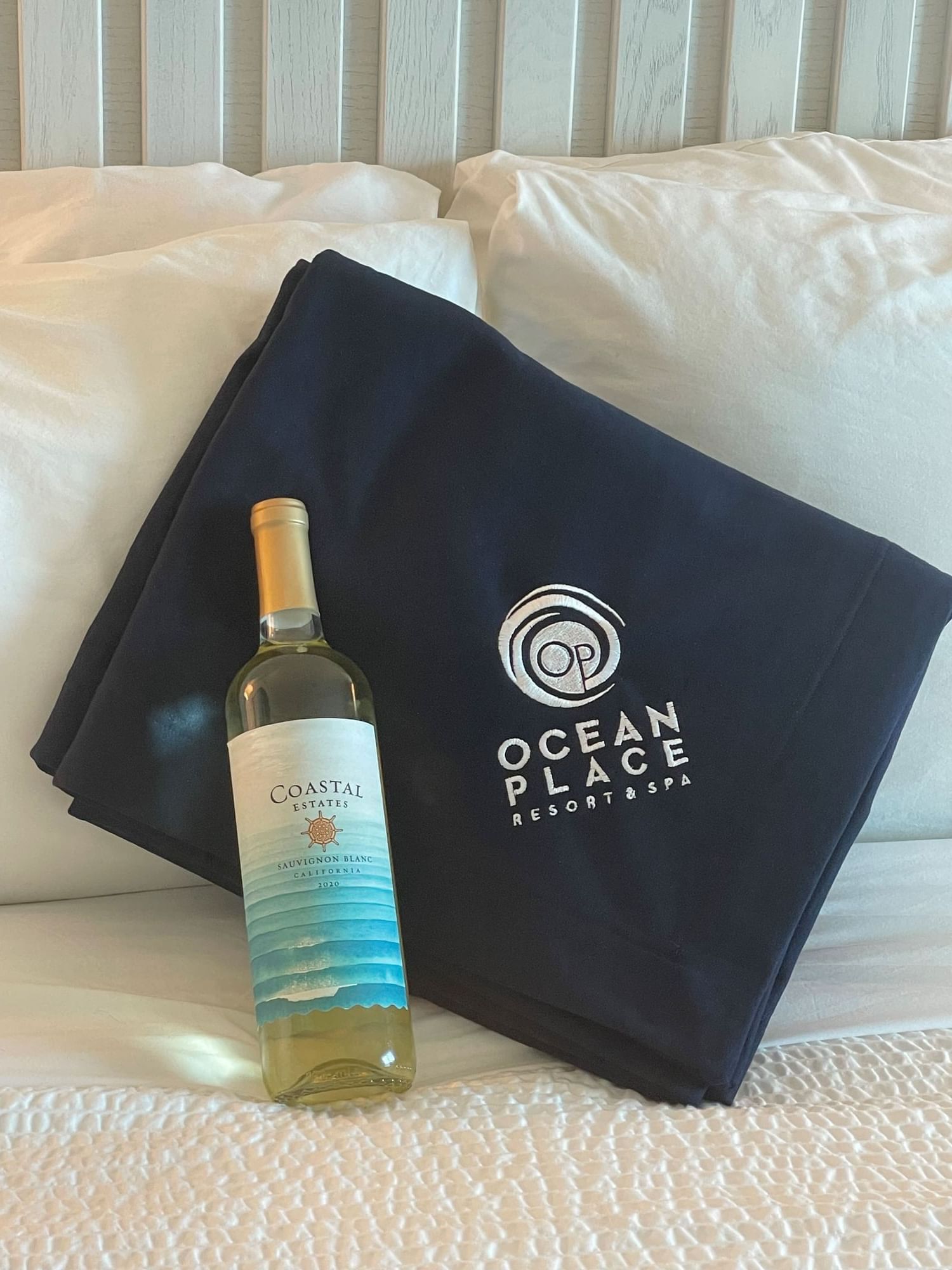 Ocean Place branded blanket in navy and a bottle of wine