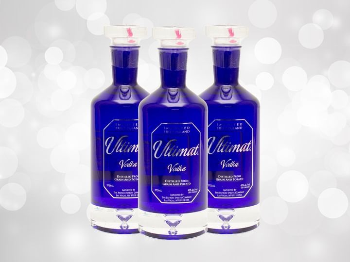 Three blue bottles of Ultimat Vodka against a silver background