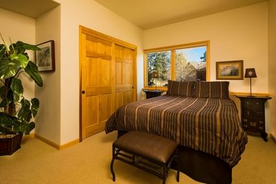 A well-lit and comfortable bedroom at The Stanley Hotel with a large bed wooden closet doors and a big window