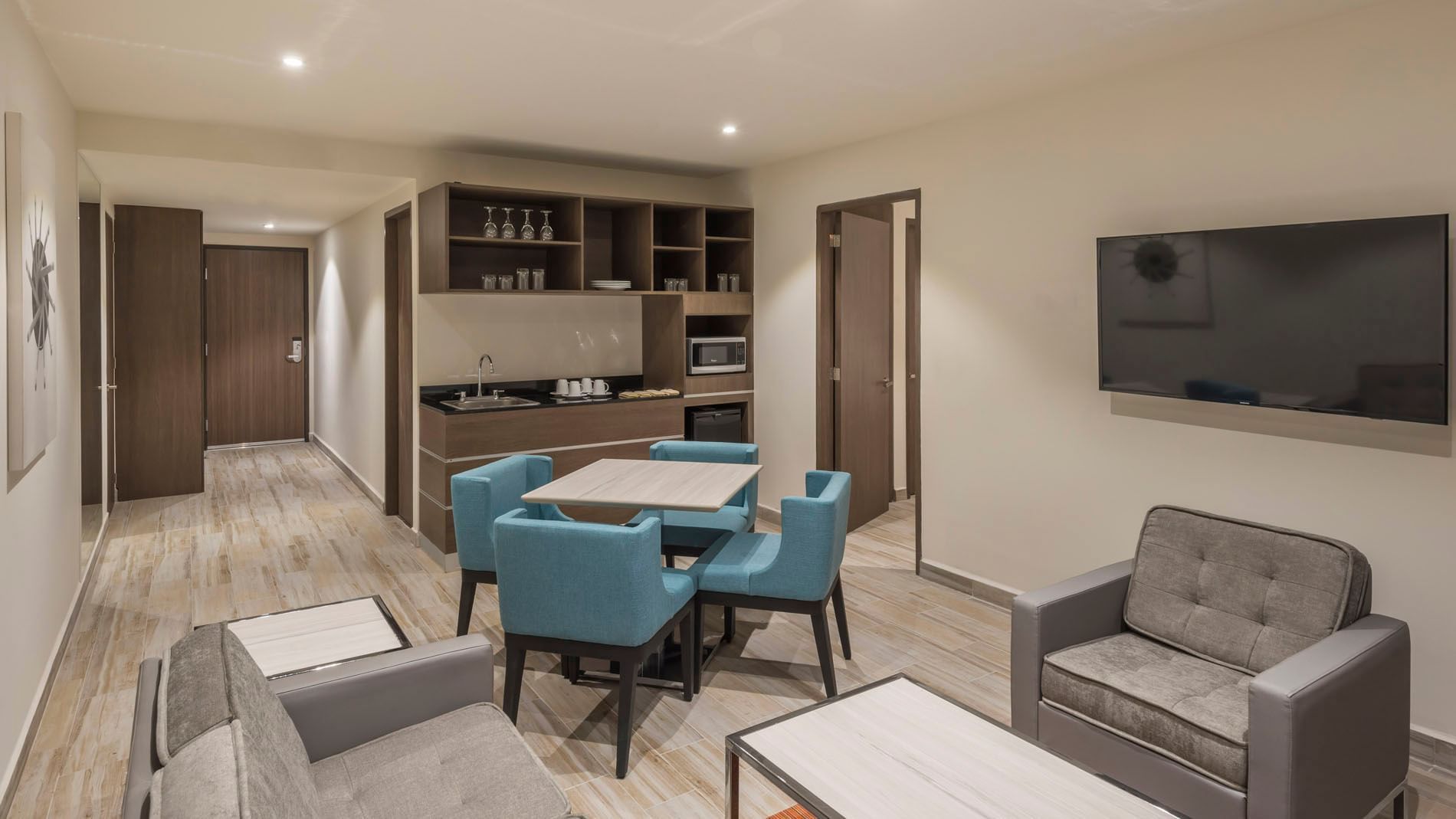 King Master Suite kitchenette and dining space with blue chairs and a microwave at Real Inn Celaya