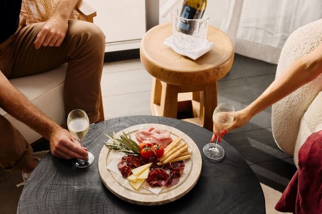 Charcuterie platter on a black table by a wine bucket under a sunny balcony layout overlooking Elysium Manly view