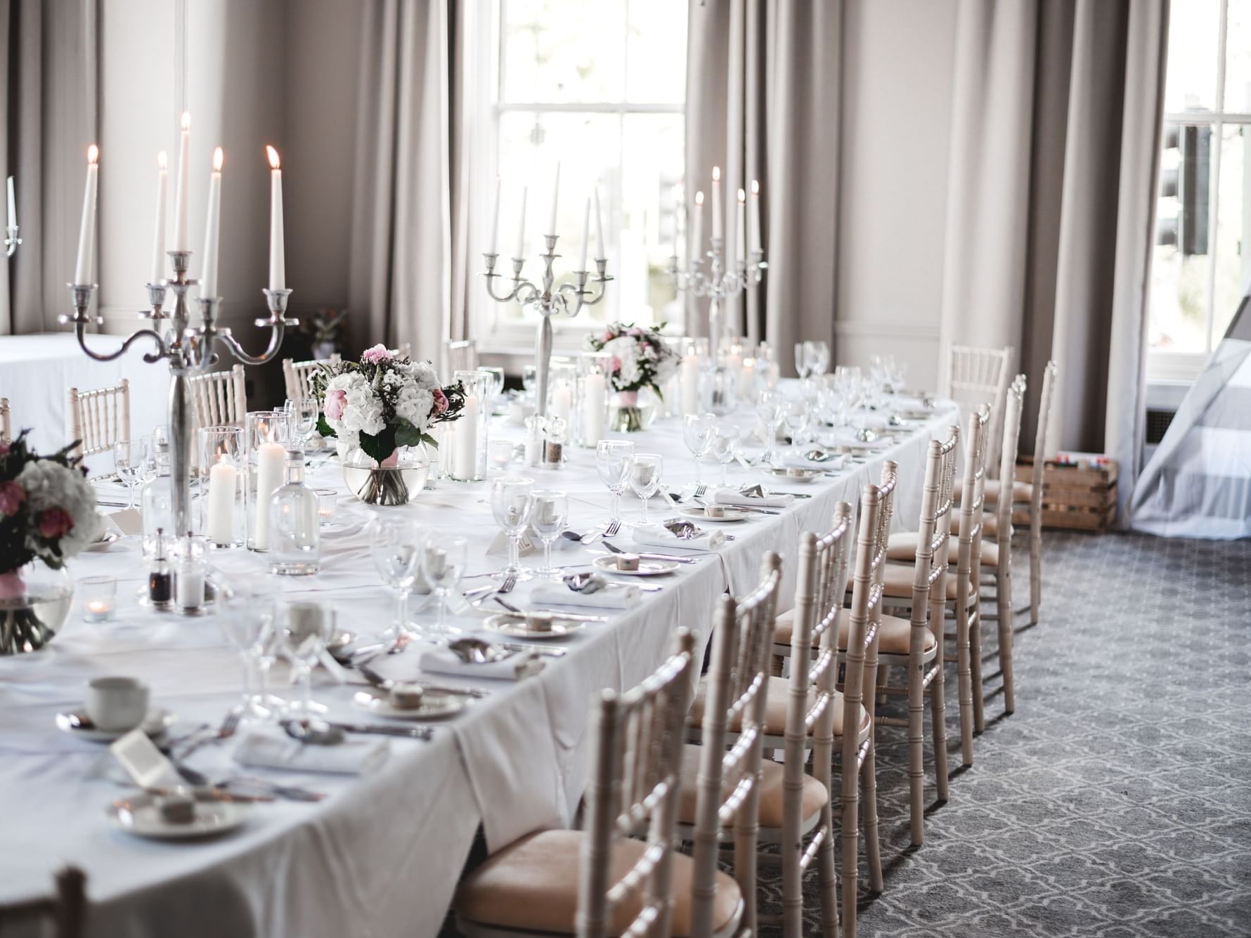 Dining setup with candelabras, flowers, and tableware in a room with large windows at The Milner York