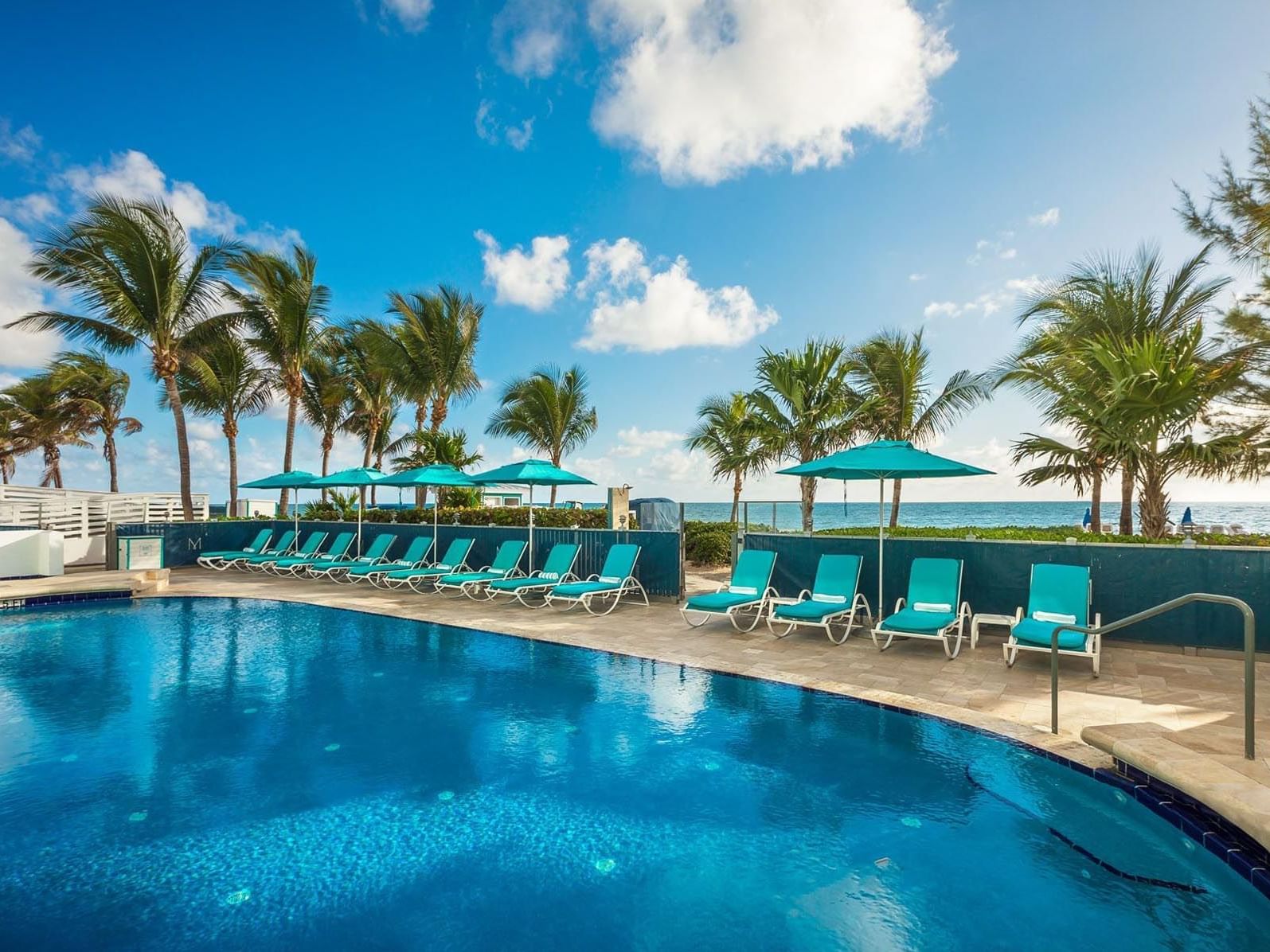 Outdoor pool with sun beds by ocean at Marenas Resort Miami