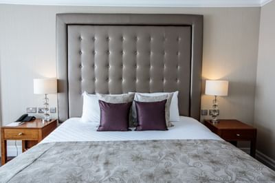 A king-sized bed in Suite at The Aberdeen Altens Hotel with a plush headboard and side tables