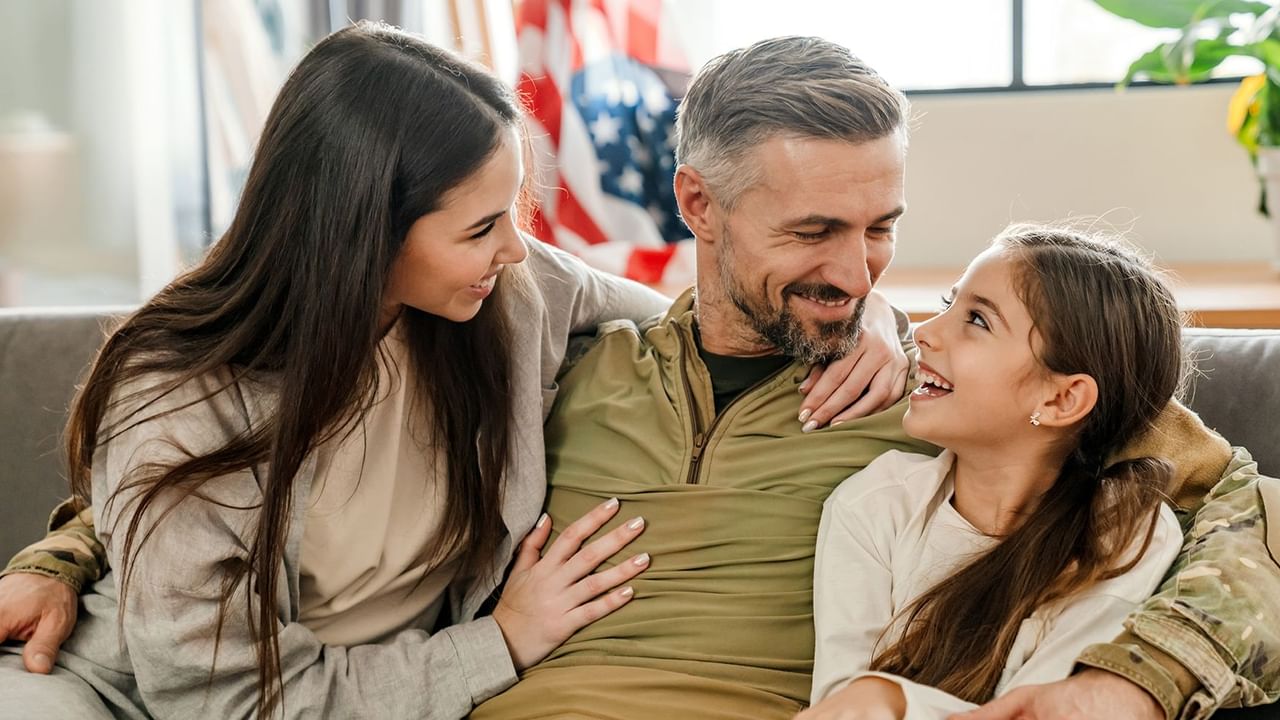 father in military fatigues with daughters in both arms