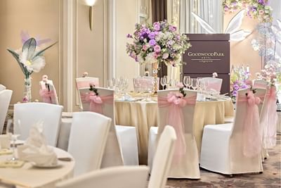 Close-up of a wedding reception table setting at Goodwood Park Hotel with pink chair bows and a lavender floral centerpiece