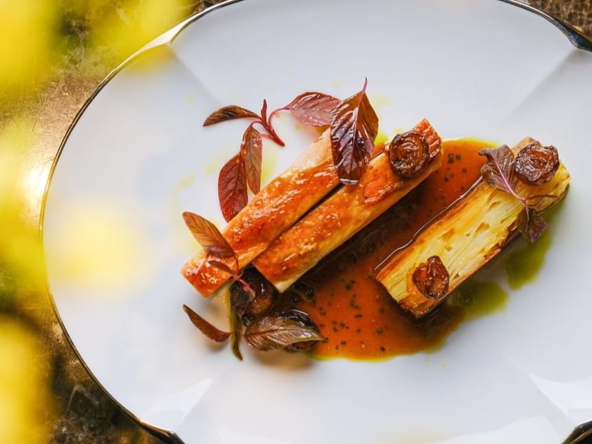 Dish plated featuring two baked potato rolls, garnished with herbs and a rich sauce at Park Hyatt Saigon
