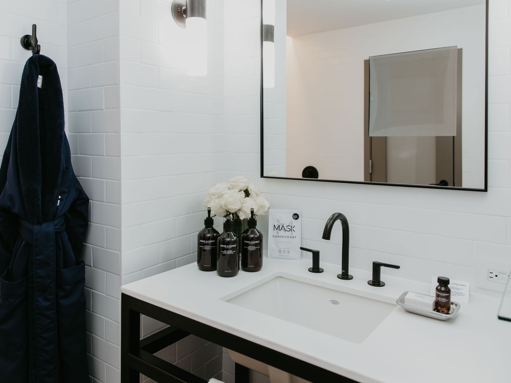 Modern bathroom sink with shower bottles, bathrobe, and a flower vase in Manhattan Suite at Gansevoort Meatpacking NYC