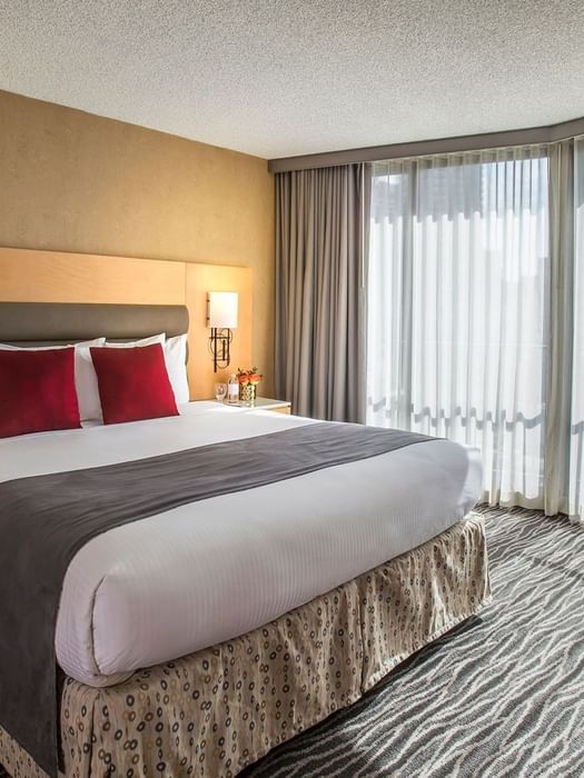A hotel room with a large bed, window, and nightstand