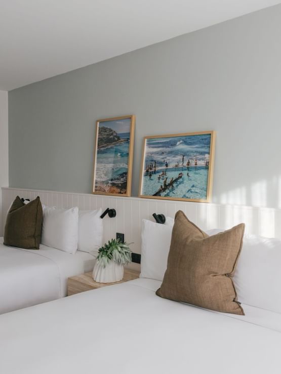 Ocean View Terrace Twin reflected in a round mirror at Elysium Manly, showing two coastal prints leaning on a headboard