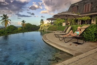 woman laying out next to pool with ocean in background