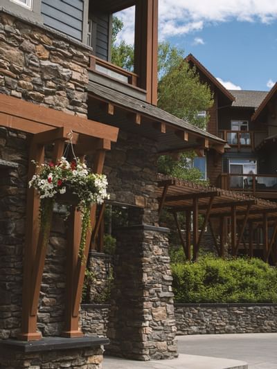 Exterior of Blackstone Mountain Lodge with a hanging flower basket, surrounded by greenery and blue skies