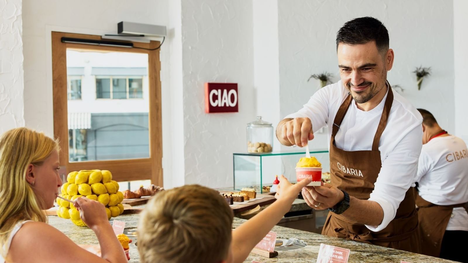 Cibaria Caffetteria & Gelateria at Elysium Manly, featuring a server by kids surrounding a curved stone counter