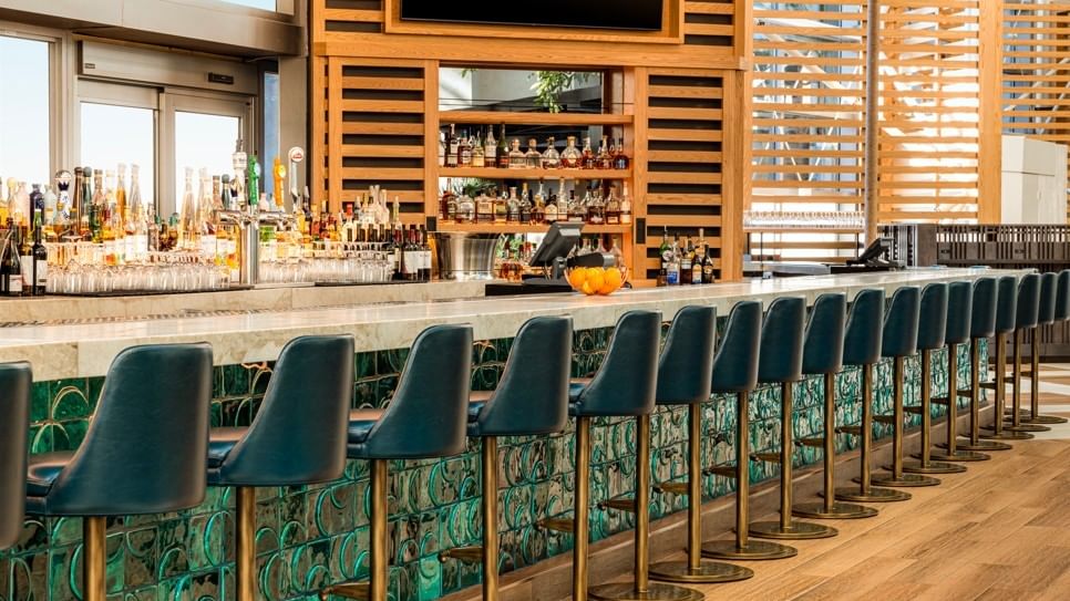 Sophisticated hotel lobby bar with marble counters, ambient lighting, and a wide selection of drinks.