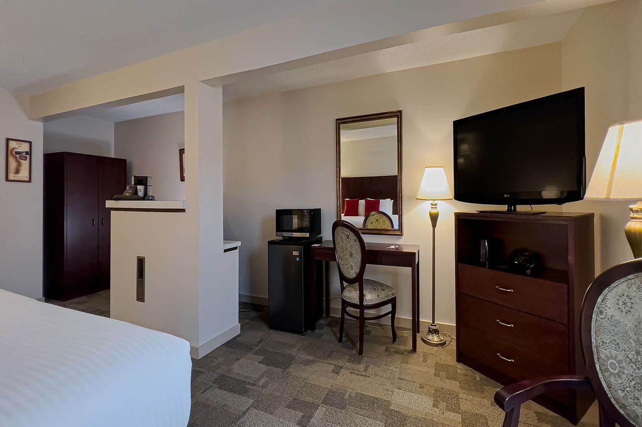 Guest room with tv, makeup table, fridge, chair