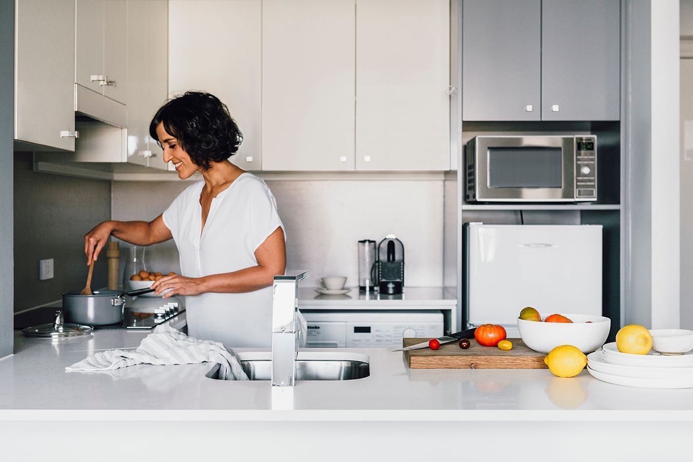 Lady preparing a meal in a Suite kitchen at Quay West Suites Melbourne