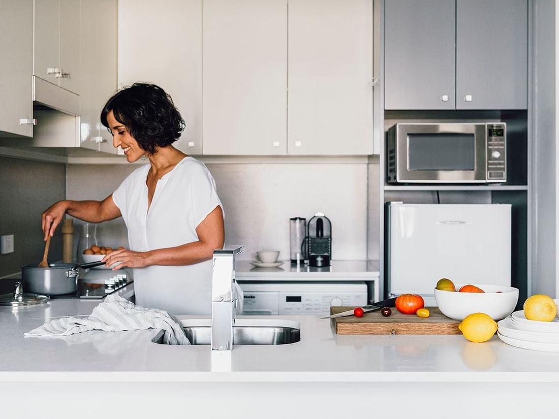 Lady cooking in 1 Bedroom Deluxe Apartment at Quay West Suites Melbourne