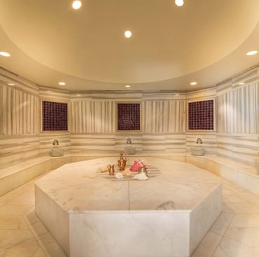 Традиционные горячие каменные лежаки, окружённые раковинами, в BeFine Spa отеля Titanic Deluxe Lara.