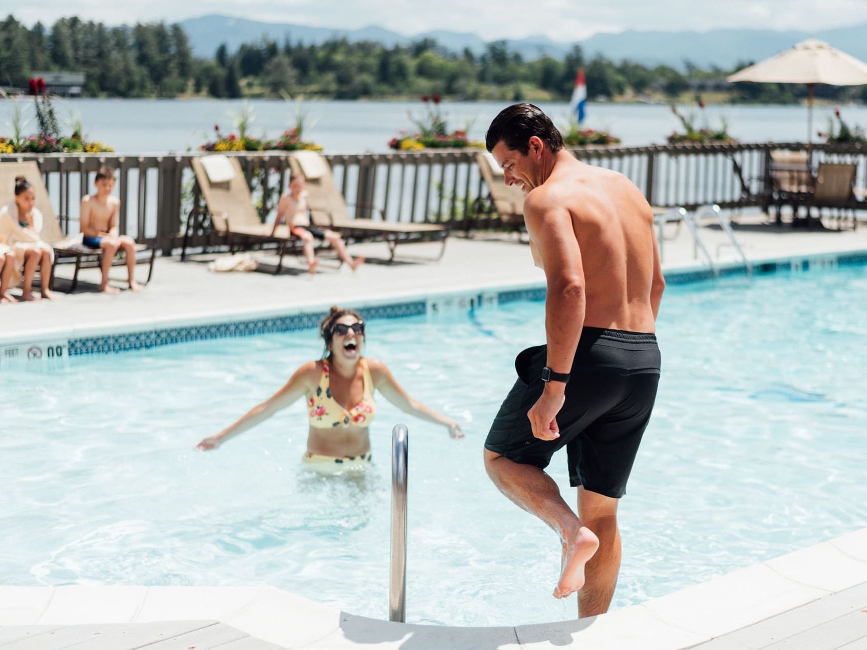 A man smiling & getting into an outdoor pool at High Peaks Resort