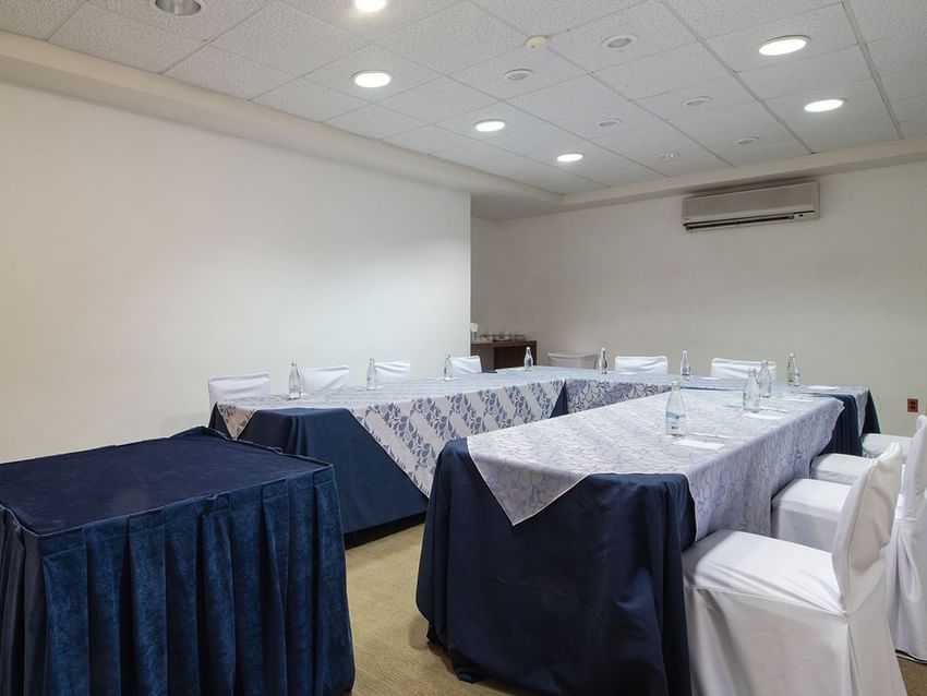 Small Oaxaca meeting room with patterned runners on blue tables and white chair covers at Camino Real Guadalajara