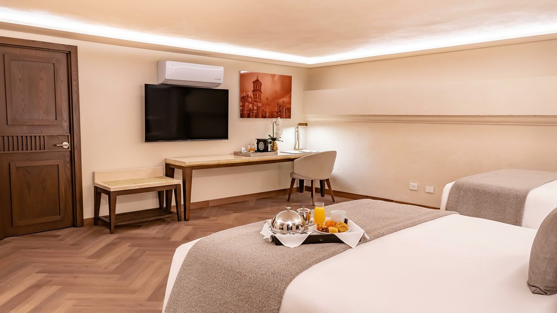 Two Queen Premium interior showing breakfast tray on the bed, a work desk, and wall-mounted TV at Quinta Real Puebla