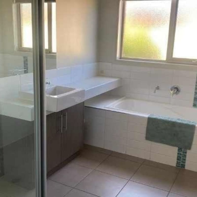 Bathroom with bathtub, sink, and window at La Trobe University Regional Housing – Mildura.