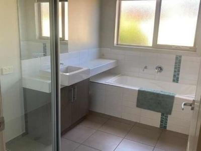 Bathroom with bathtub, sink, and window at La Trobe University Regional Housing – Mildura.