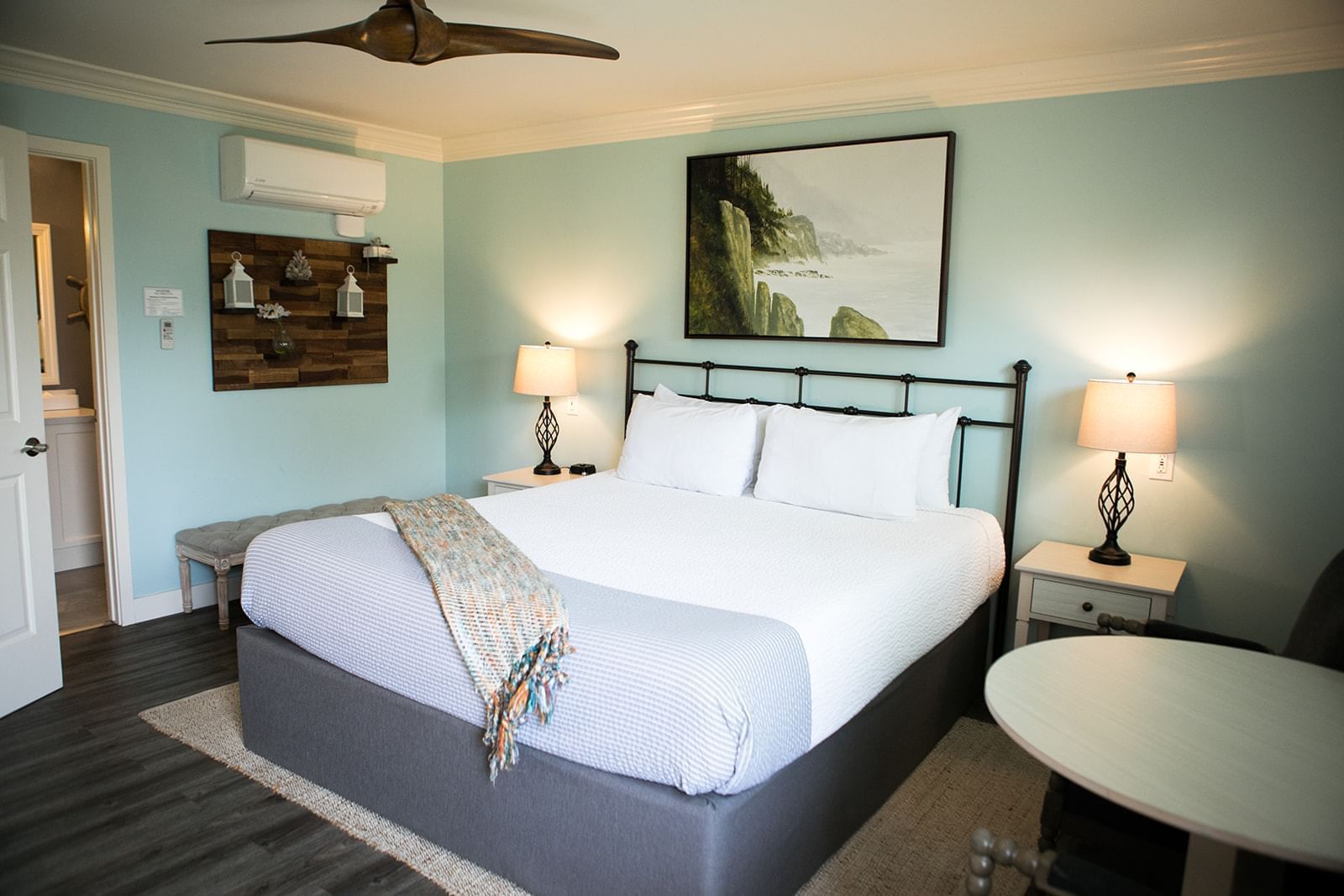A hotel room with a king-sized bed, two nightstands with lamps, and a painting on the wall.