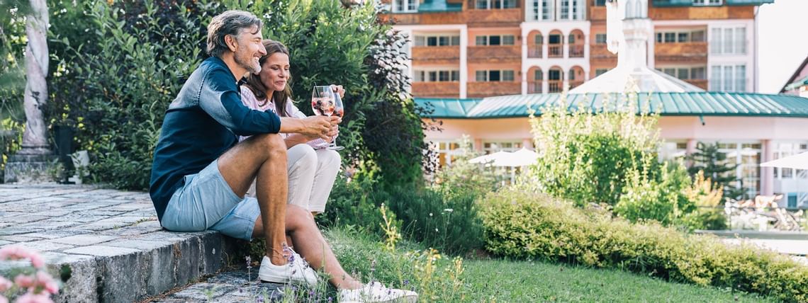 Gäste bei einem Glas Wein im sommerlichen Aussenbereich des Wellnesshotel Liebes Rot Flüh, Tannheimer Tal
