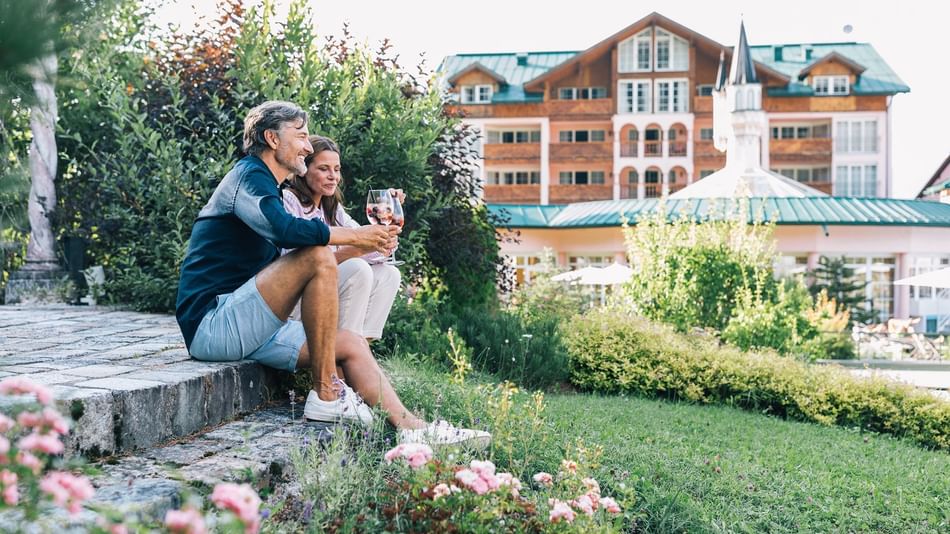Gäste bei einem Glas Wein im sommerlichen Aussenbereich des Wellnesshotel Liebes Rot Flüh, Tannheimer Tal