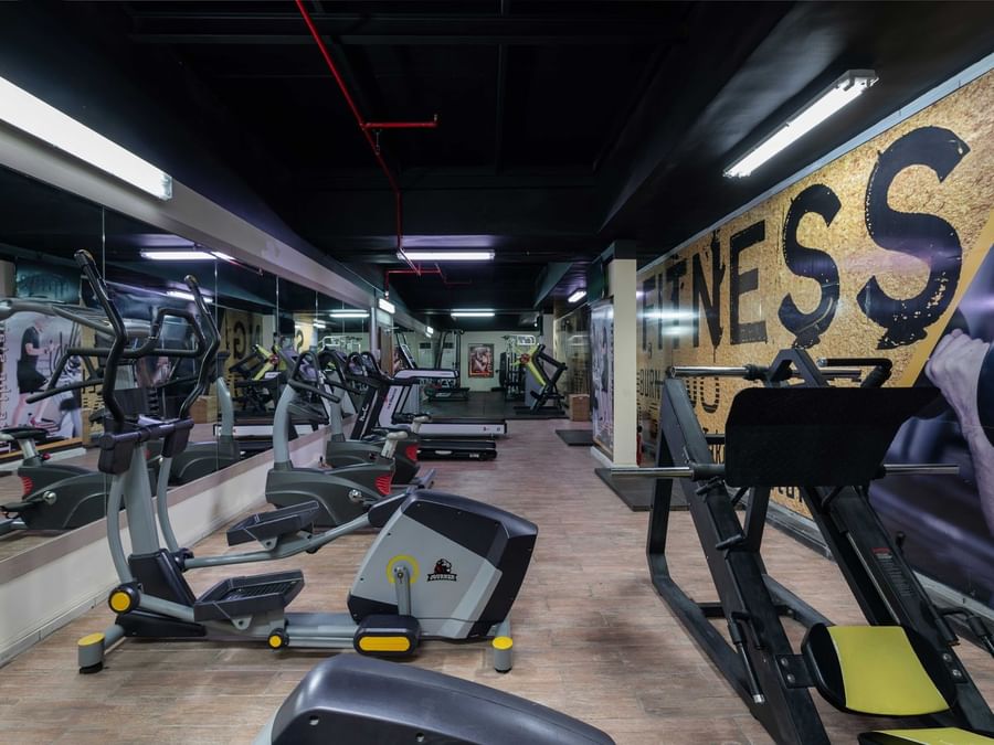 Elliptical machines, a leg press, and treadmills under long ceiling lights in the Fitness Centre at Warwick Hotel Jeddah